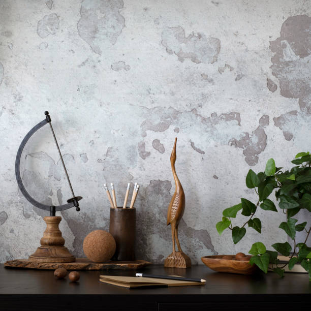istock Creative composition of home office interior with black desk, ornaments on the wall, gray concrete wall, pencil holder, plants in flowerpots and office accessories. Home decor. Template. 1542734887