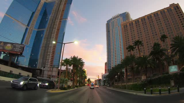 Driving POV on the boulevard in Las Vegas with view of the casino and hotel buildings and commertial lights at sunset