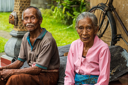 Bali-, Indonesia-- Feb 27, 2023. Photo of a man and woman sitting on a porch in a family compound in Bali. in Bali,