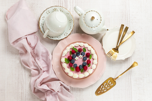 White cake with pink elements made from pastry mastic on a white background. Sugar flowers, marzipan flowers and mastic, beautiful decor for decorating cakes. For a menu or a confectionery catalog.