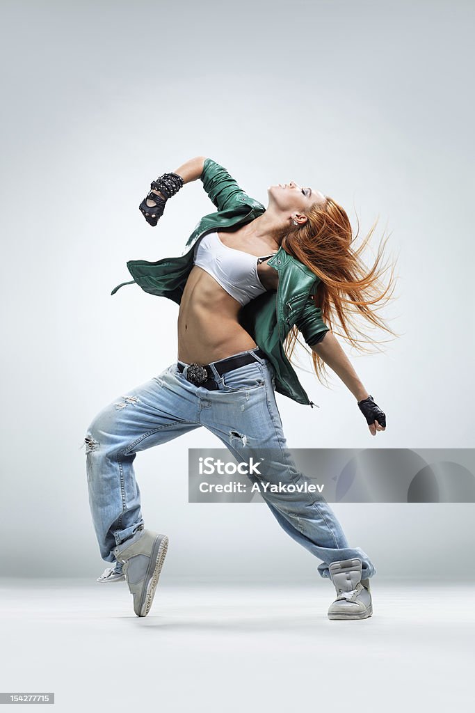 A woman dancing in jeans and an open jacket modern style dancer posing on studio background Dancing Stock Photo