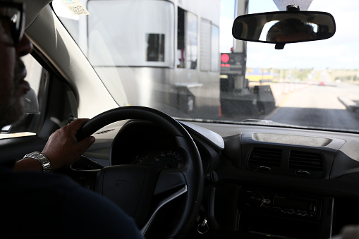 candeias, bahia, brazil - june 30, 2023: a driver is seen inside his vehicle next to a toll collection plaza on federal highway BR 324.