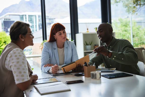 istock Business people, meeting in conference room with notes, collaboration at startup for project and workshop ideas. Employees working together, black man and women in communication, agenda and teamwork 1542784804