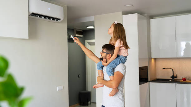 istock Father with daughter on shoulders turn on air conditioner using remote control 1542800522
