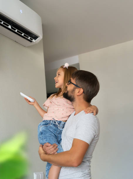Father and daughter turn on air conditioner using remote control. Cooler system Happy family, father and little daughter fun turn on air conditioner using remote control. Cooler system air conditioner family stock pictures, royalty-free photos & images