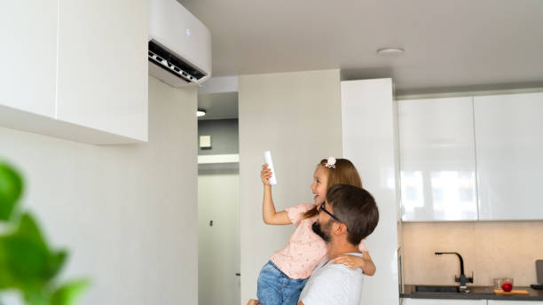 istock Father and daughter turn on air conditioner using remote control in apartment 1542800534