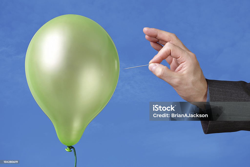 A pin being used to pop a green balloon Needle about to pop a green balloon Balloon Stock Photo