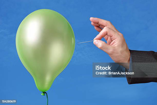 A Pin Being Used To Pop A Green Balloon Stock Photo - Download Image Now - Balloon, Exploding, Straight Pin