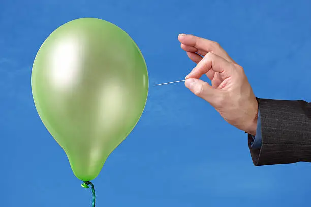 Photo of A pin being used to pop a green balloon