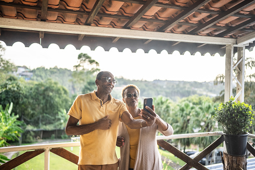 Senior couple doing a video call on mobile phone in the hotel balcony