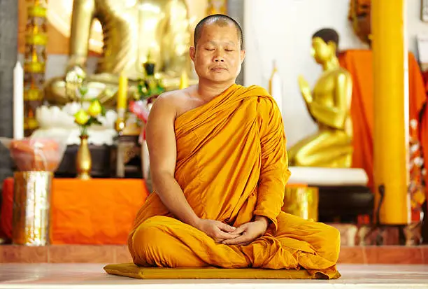 Photo of Meditating monk in a sacred shrine