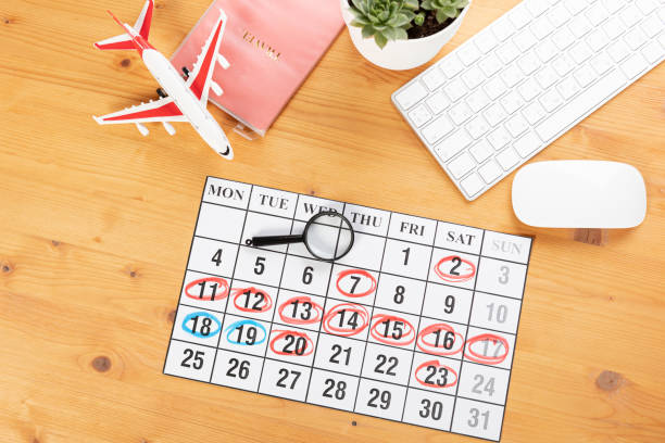 istock Calendar and reminders for work trips, travel and vacations. glider on desktop with airplane and magnifying glass pen, keyboard. mark important plans in a diary at the office desk. 2023 calendar reminder concept. 1542885964