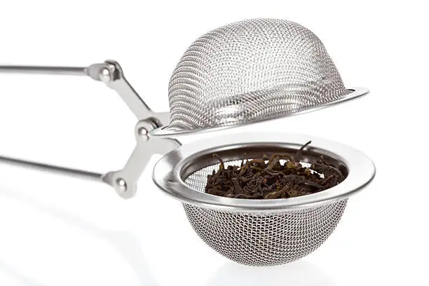 Tea infuser with Green Tea leaves close up