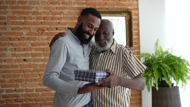 Adult son giving gift to senior father
