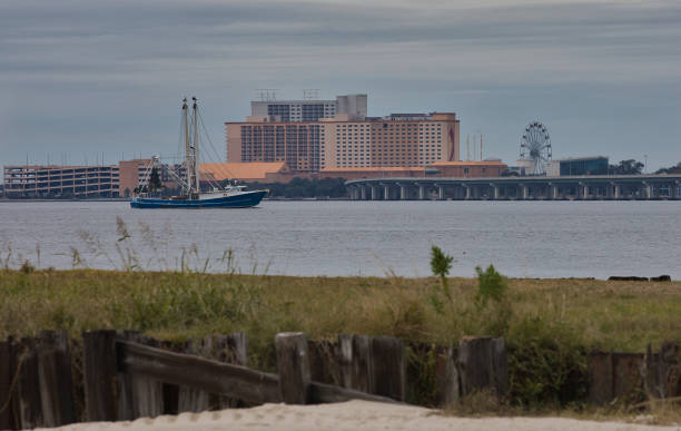 Shrimp Trawler on the Bay of Biloxi with a casino and a Ferris wheel and a bridge in the background.
