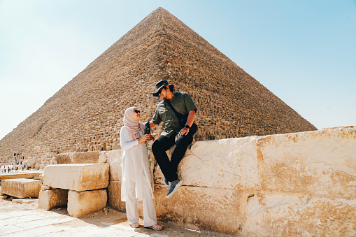 asian  muslim couple  standing on desert on the background of Giza pyramids