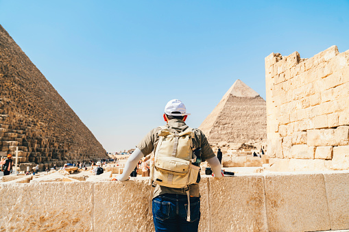 Egypt, Cairo, asian man tourist standing with Great Pyramid of Giza in background