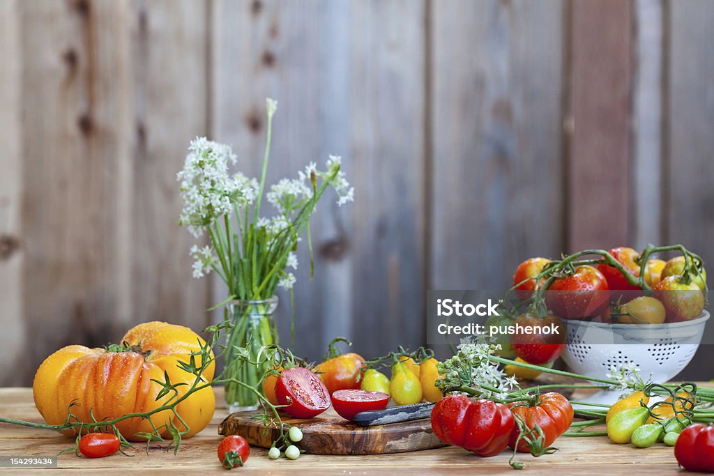 Lots of fresh tomatoes and garlic flowers with wooden background Agriculture Stock Photo