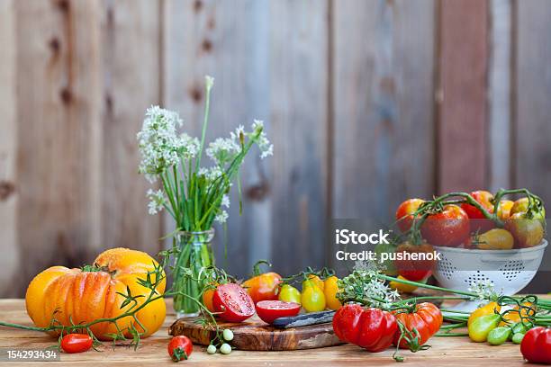 Lots Of Fresh Tomatoes And Garlic Flowers With Wooden Background Stock Photo - Download Image Now