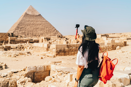 asian Woman standing on desert on the background of Giza pyramids