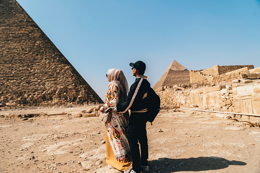 asian couple  standing on desert on the background of Giza pyramids