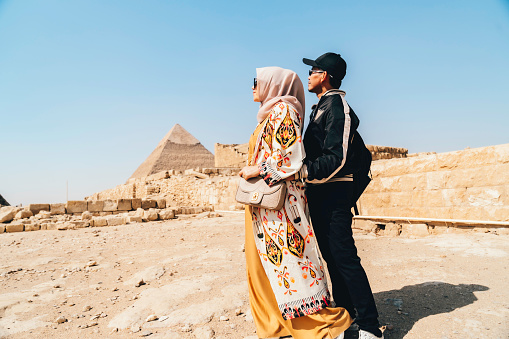 asian couple  standing on desert on the background of Giza pyramids