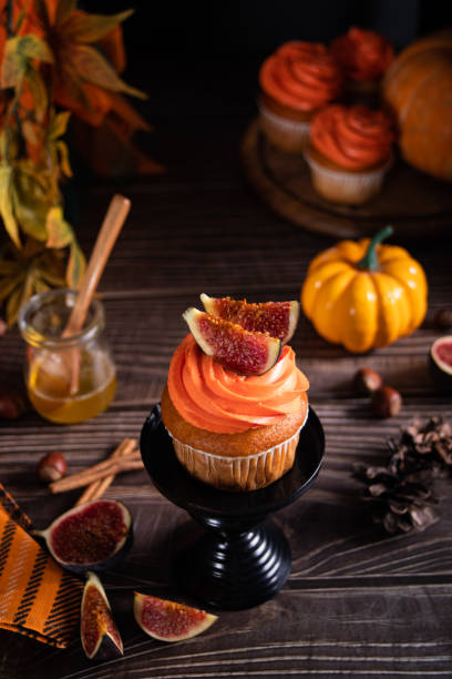 Delicious homemade autumn season spicy pumpkin cupcakes with whipped orange cream with fruit figs. stock photo