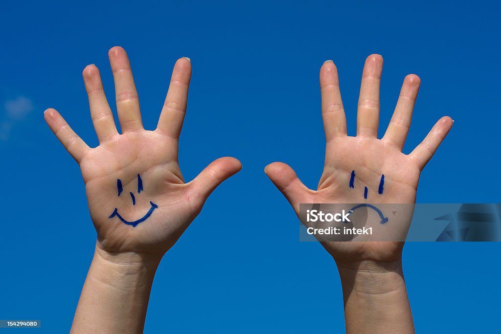 Hands with smiles and sadness pattern Hands with smiles and sadness pattern against the blue sky Blue Stock Photo