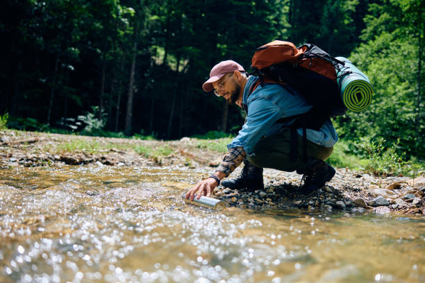 istock Young hiker taking fresh water from pure mountain creek. 1542956428