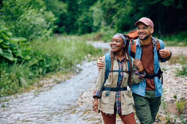 istock Happy couple with backpacks embracing while hiking in nature. 1542959957