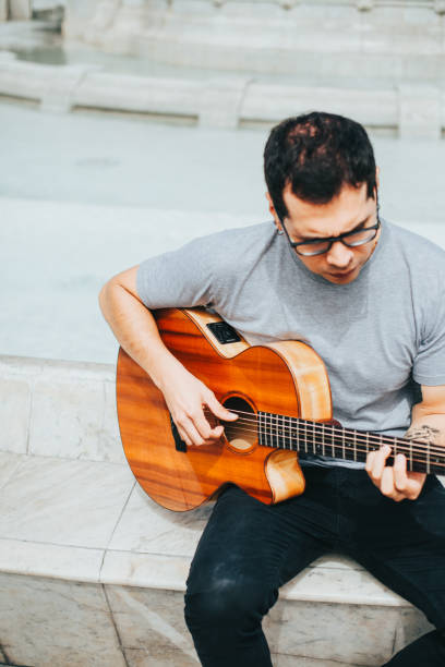 istock Man playing acoustic guitar sitting in a park. 1543050839