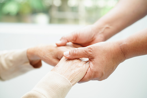 Caregiver holding hands Asian elderly woman patient, help and care in hospital.