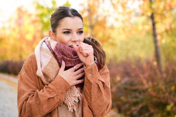 Caucasian woman coughing during autumn. stock photo