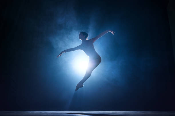istock Expressive, artistic young woman, professional ballerina making creative performance against dark blue background with spotlight 1543089097