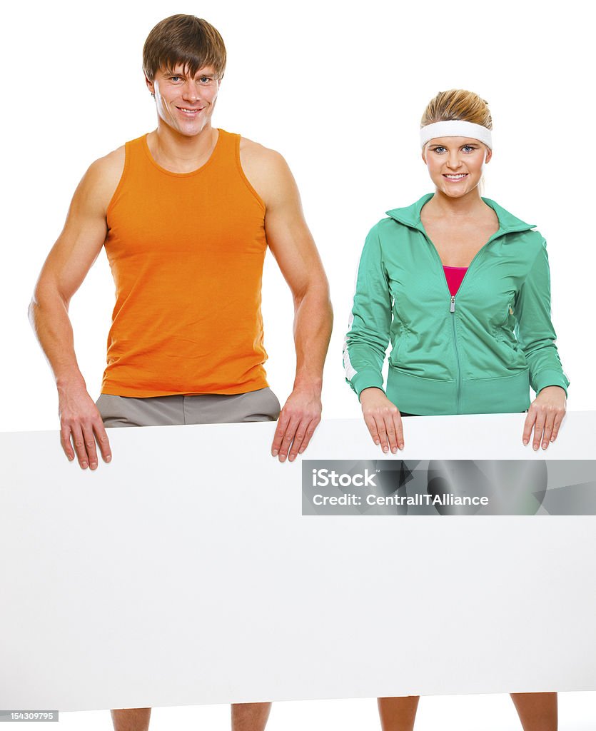 Fitness girl and male athlete with blank billboard Fitness girl and male athlete with blank billboard isolated on white Adult Stock Photo