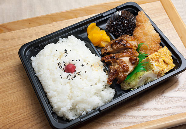 Japanese Cuisine Chicken Teriyaki　Bento Bento (弁当 bentō) is a single-portion takeout or home-packed meal common in Japanese cuisine. A traditional bento consists of rice, fish or meat, and one or more pickled or cooked vegetables, usually in a box-shaped container. Containers range from disposable mass produced to hand crafted lacquerware. Although bento are readily available in many places throughout Japan, including convenience stores, bento shops (弁当屋 bentō-ya), train stations, and department stores, it is still common for Japanese homemakers to spend time and energy for their spouse, child, or themselves producing a carefully prepared lunch box. packed lunch photos stock pictures, royalty-free photos & images