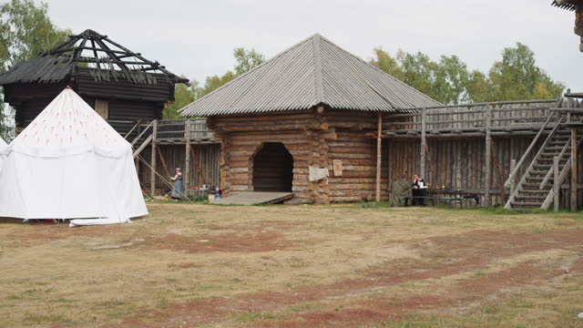 Medieval courtyard with wooden arch near gate and white tent