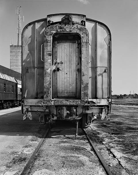 This is a vertical black and white photograph taken with 4x5 film. The train car is unhitched and sits at the end of the railroad tracks.