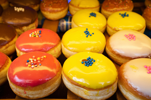 Various colorful donuts on the shelf in the pastry shop