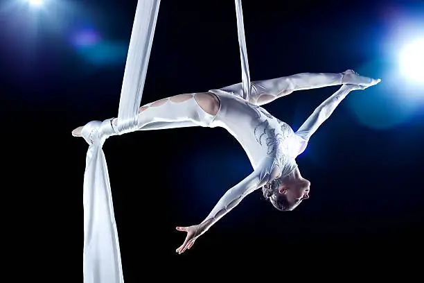 Young woman gymnast. On black background with flash effect.