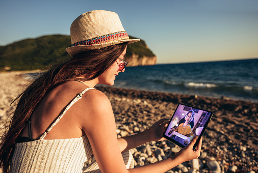 Teenage girl using digital tablet to watch video online on the beach