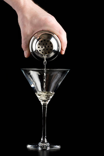 Cocktail being poured from a shaker into a martini glass