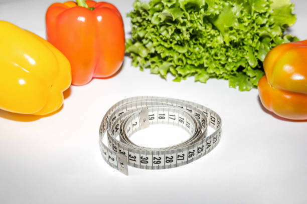 Concept of healthy lifestyle and proper nutrition. Red and yellow bell peppers with a measuring tape.