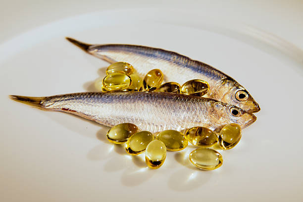 sprat fisch und lebertran kapsel - cod liver oil fish oil vitamin e vitamin pill stock-fotos und bilder