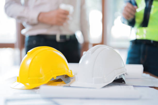 istock yellow and white helmet image For use on the table, there is a blueprint. Behind it, there is an engineer or architect talking about the design industry. Wear vests and uniforms. in the workplace 1543307161