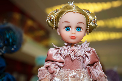 The head of a blue-eyed doll toy in beautiful clothes close-up.
