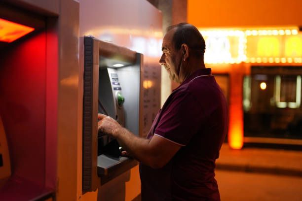 senior man makes deposits at atm in the evening