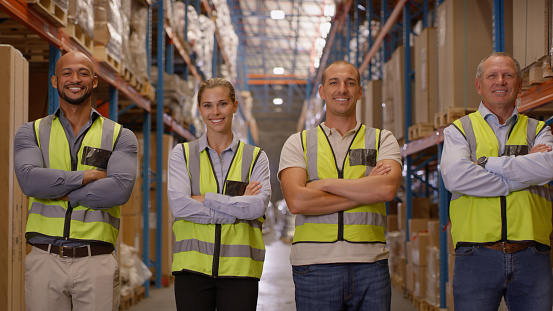 Happy team, logistics and arms crossed in warehouse for supply chain management or inventory. Group portrait of people, storage managers or leadership for mass production, delivery or courier service