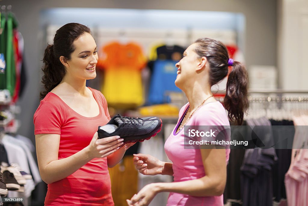 shop assistant helping customer friendly shop assistant helping customer choosing sports shoes Customer Focused Stock Photo