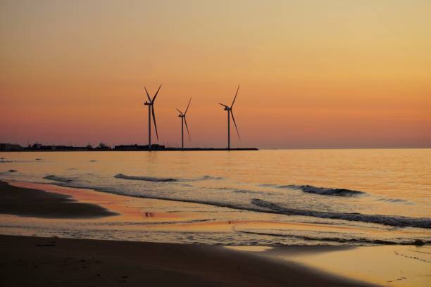 Windmills at sunset on the beach of Denmark. Sunset on the beach with windmills. Green energy in Denmark. Windmills stand on the beach after sunset.